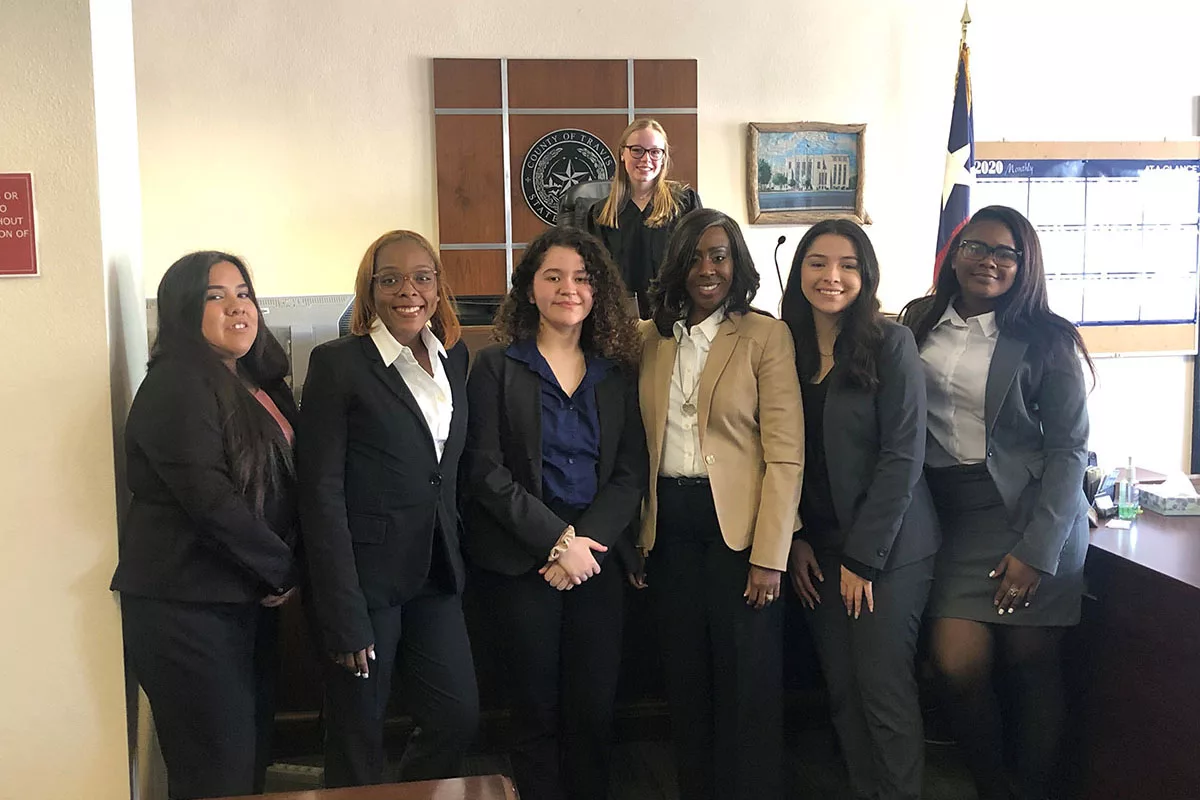 Six young professional dressed in suits pose in front of a State Representative's desk